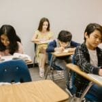 Children focused on writing and learning in a classroom environment.