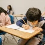 A group of children focused on writing and studying in a classroom setting, emphasizing learning and education.