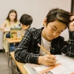 Students diligently working in a classroom, showcasing educational focus and concentration.