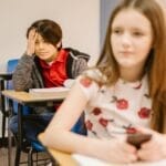 Two students in a classroom setting, focused on their studies.