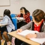 Diverse group of students engaged in study session inside a classroom setting.