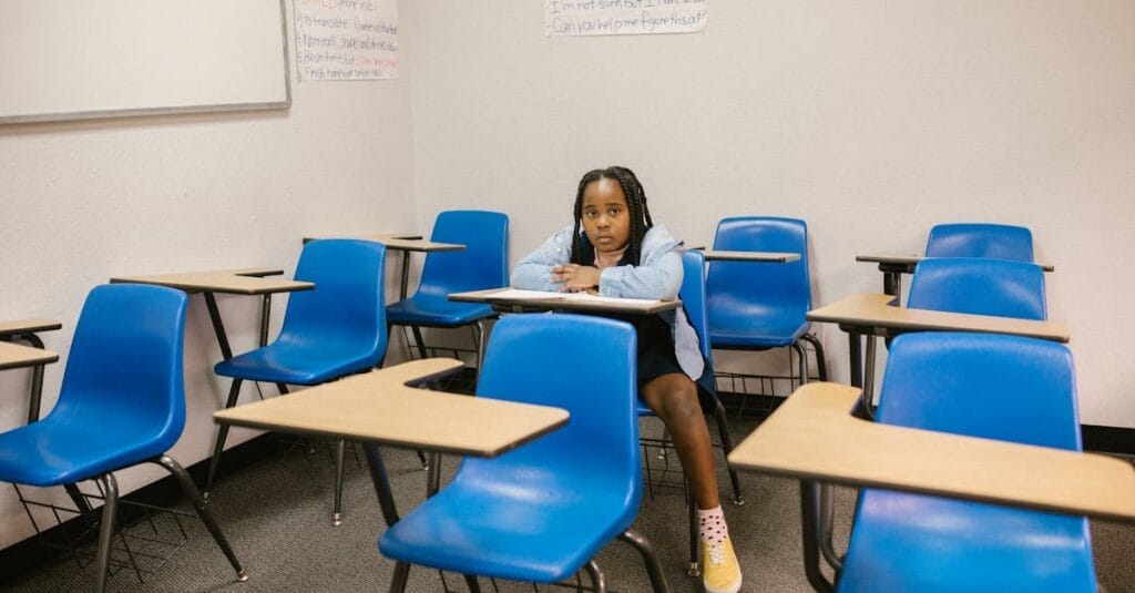 A young girl sits alone in an empty classroom, symbolizing bullying and solitude.