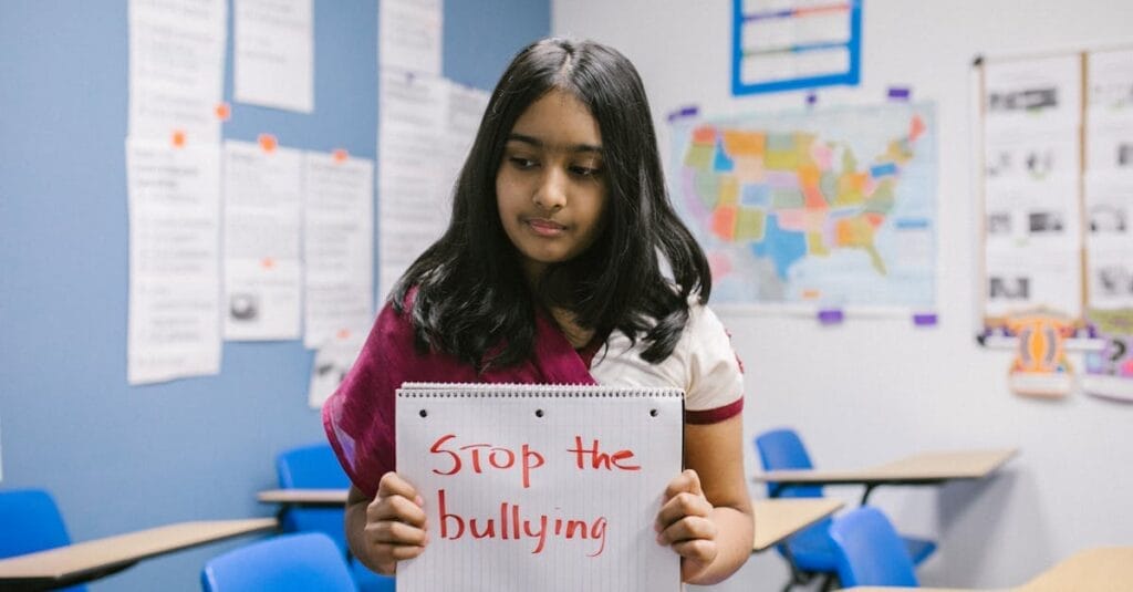 A schoolgirl holds a 'Stop the bullying' sign in a classroom to raise awareness against bullying.