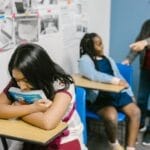 A sad girl in a classroom being bullied by classmates, highlighting anti-bullying awareness.