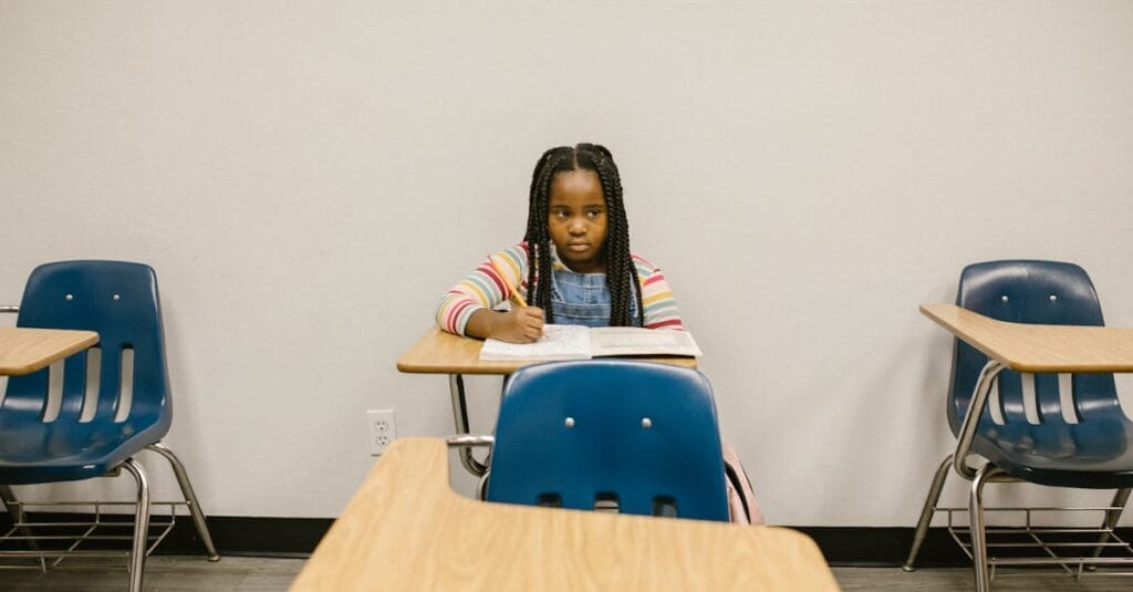 A young girl sits alone in a school classroom, symbolizing the impact of bullying.