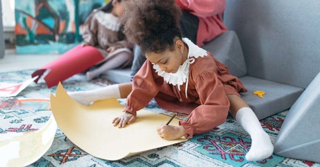 Child drawing on paper in an indoor art setting, fostering creativity.