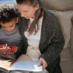 A grandmother and grandson sharing a cozy reading moment on a sofa indoors.