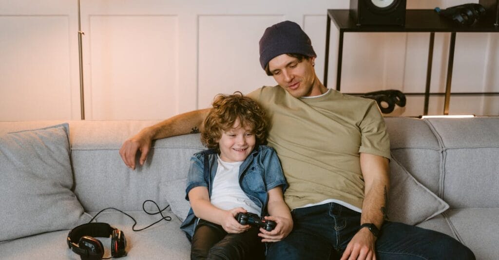 Father and son bonding over a video game session on the sofa at home.