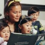 A joyful family bonding over a book at home, highlighting motherhood and togetherness.