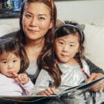 Cozy family moment with a mother reading a book with her daughters on a couch.