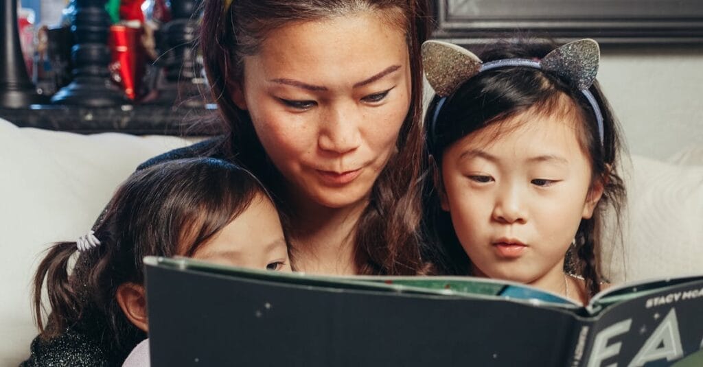 A mother enjoys quality reading time with her young daughters, bonding at home.