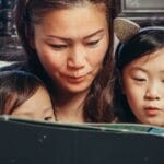 A mother enjoys quality reading time with her young daughters, bonding at home.