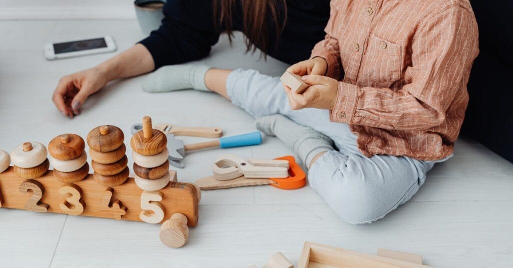 Child plays with educational wooden toys indoors, promoting learning and creativity.