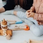 Child plays with educational wooden toys indoors, promoting learning and creativity.