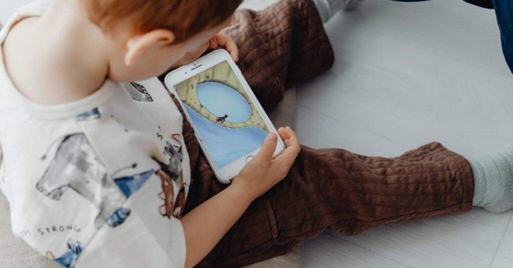 A young child playing an educational game on a smartphone indoors, focused on learning.