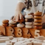 Child's hand interacting with wooden educational toys and number blocks indoors.