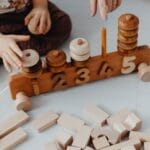 Child engaging with wooden blocks and train toy for learning numbers interactively.