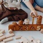 A child engaging with wooden educational toys, counting blocks indoors.