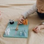 A child and adult enjoying a colorful animal-themed board game on a cozy setting.