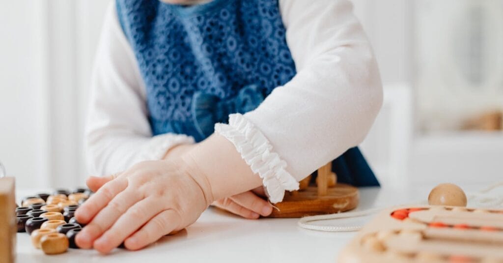 A young child playing with wooden educational toys indoors, fostering creativity and learning.