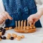 A child interacts with a wooden sorting toy, developing fine motor skills and learning through play.