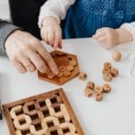 A father and child engaging with wooden educational toys at a table indoors.