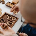 Adults and children playing with intricate wooden puzzles on a white table, fostering creativity.