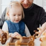 A father and daughter enjoying quality time playing with wooden toys indoors.