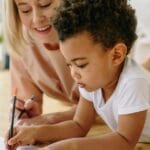 Mother and son bonding through drawing at home, fostering creativity and connection.