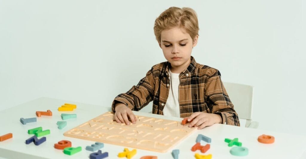 Blonde child engaging with educational alphabet toys at a table indoors.