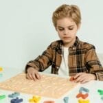 Blonde child engaging with educational alphabet toys at a table indoors.