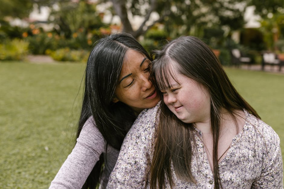 A loving mother embraces her daughter with Down syndrome in a serene outdoor setting.