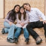 A loving family enjoys a bonding moment together, sitting on decorative outdoor stairs.