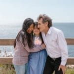 Family shares a loving embrace by the ocean, highlighting connection and joy.