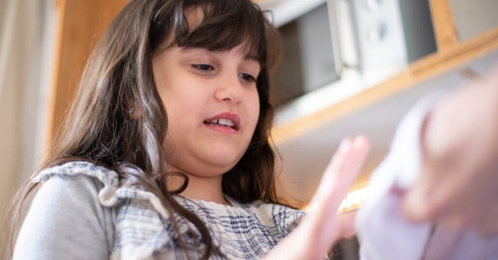 A young girl interacting with a toy or object indoors. Captures a candid moment with natural lighting.