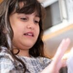 A young girl interacting with a toy or object indoors. Captures a candid moment with natural lighting.