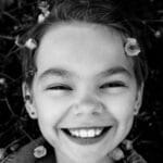 Charming black and white portrait of a smiling child surrounded by nature.