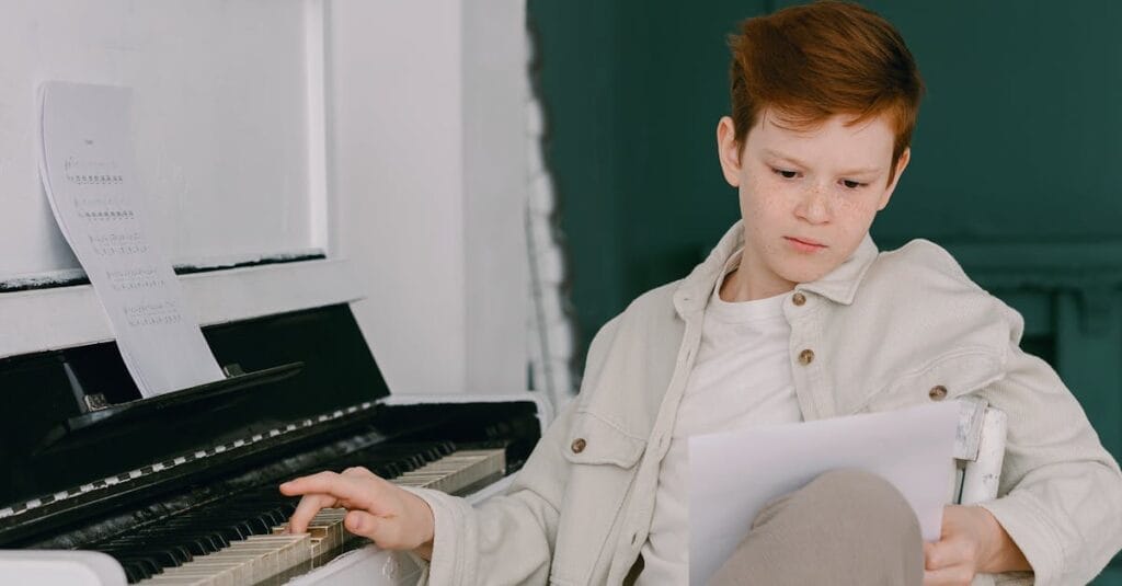 A young boy studying a piano sheet indoors, enhancing musical skills.
