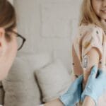 A young girl receives an insulin checkup from a medical professional at home, managing diabetes.