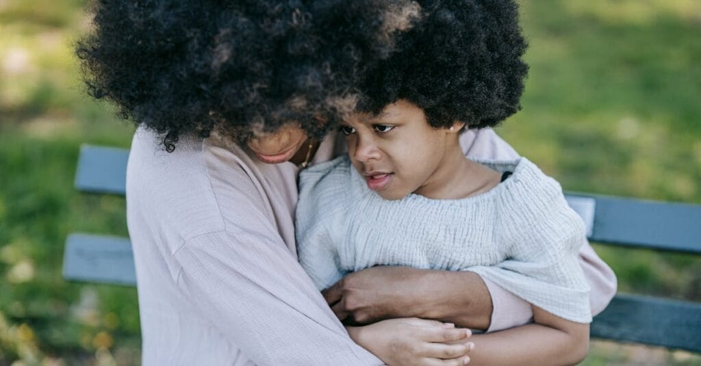 Mother and child sharing a tender embrace on a sunny day in the park.