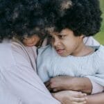 Mother and child sharing a tender embrace on a sunny day in the park.