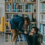 A child bullies another student in a school library, highlighting social issues.