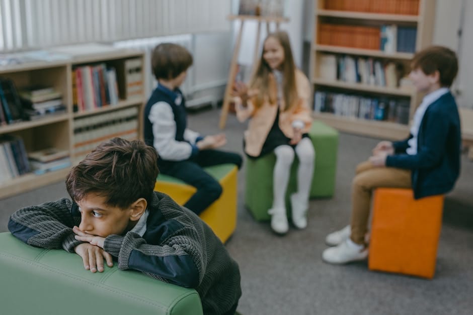 A sad child isolated in a school library while peers chat in the background.