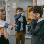 Group of children bullying a classmate in a school library setting.