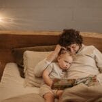 A father and child enjoy quality time reading a bedtime story in a cozy bedroom setting.