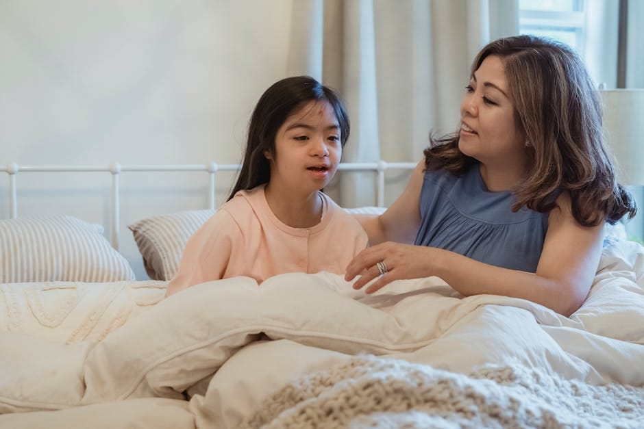 A mother lovingly embraces her daughter in a cozy bedroom setting, expressing warmth and care.