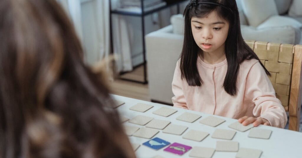 Young girl with Down syndrome focuses on a memory game at a home table.