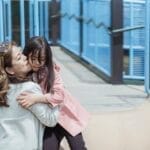 A heartwarming moment between a mother and daughter enjoying time together at a sunny playground.