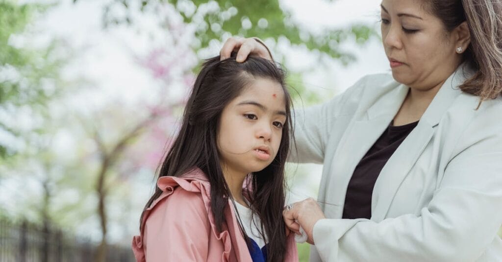 Mother gently helps her daughter adjust her hair during outdoor quality time.