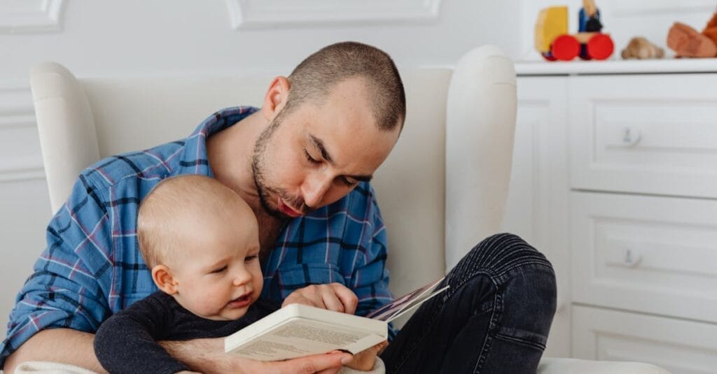 A father and his baby enjoy a bonding moment while reading together indoors.